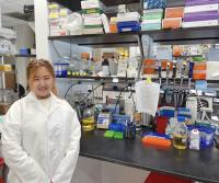 Qiaosi (Tracy) Tang, PhD, pictured in the laboratory in front of laboratory equipment
